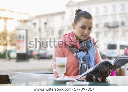 Young Woman Reading Book At Sidewalk Cafe