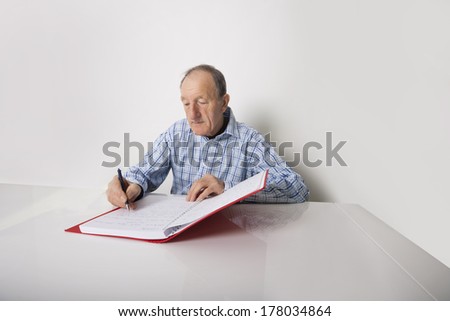 Senior businessman writing in file at desk