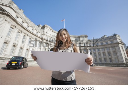 Portrait of happy young woman holding map against Admiralty Arch in London; England; UK