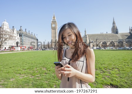 Young woman text messaging through smart phone against Big Ben at London; England; UK
