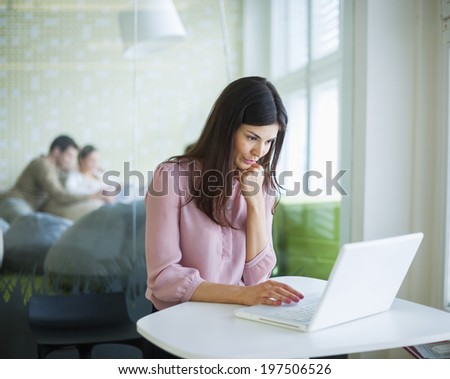 Young businesswoman using laptop at office table