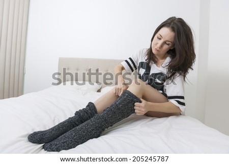 Full length of young woman wearing socks in bed