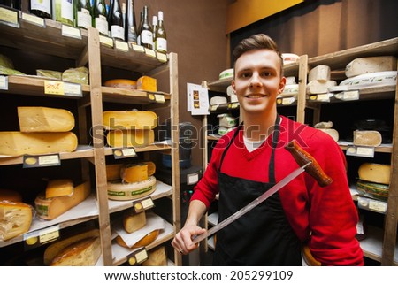 Portrait of confident male salesperson holding knife in cheese store