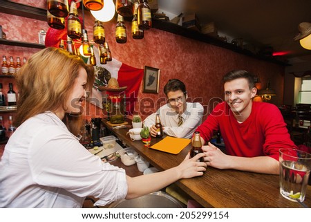 Female bartender serving beer to men at bar counter