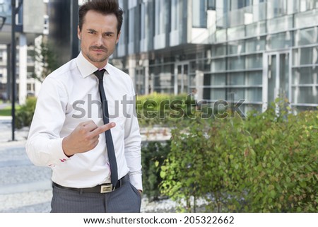 Portrait of angry businessman showing middle finger outside office building