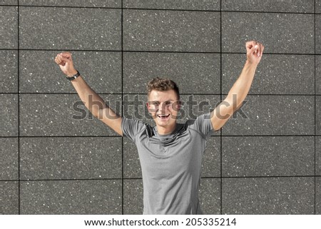 Portrait of successful male jogger with clenched fist against tiled wall