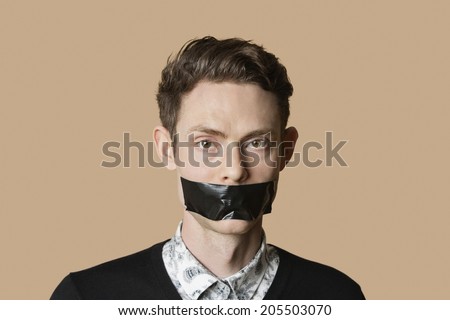 Portrait of a mid adult man with tape on mouth over colored background