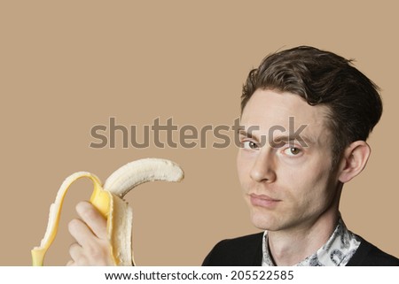 Portrait of a mid adult man holding banana over colored background