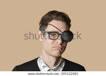 Portrait of a man wearing eye patch on glasses over colored background