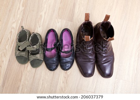 High angle view of family shoes placed in a row on hardwood floor
