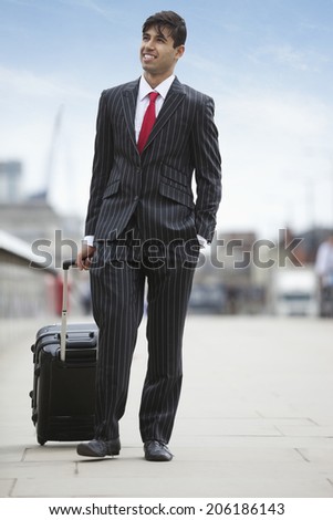 Young Indian businessman with luggage trolley bag on street