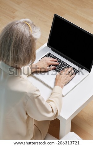 Senior woman surfing the net on laptop at home