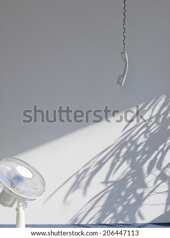 View of a telephone receiver and fan in an empty room