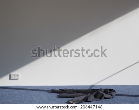 View of a coat on carpeted floor against white wall
