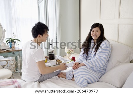Man giving rose to woman in bed