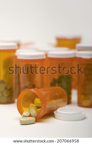 Bottles of pills, one spilling, close-up