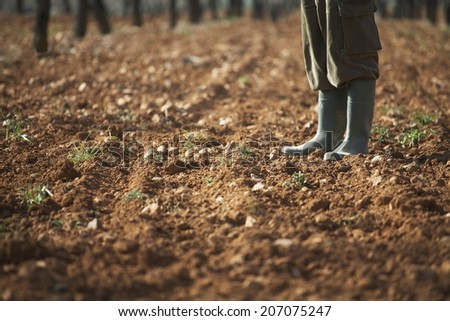 Low section of farmer standing on fertile soil in farm