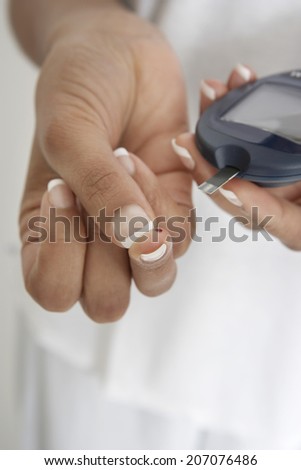 Woman taking diabetes test, close-up of hands