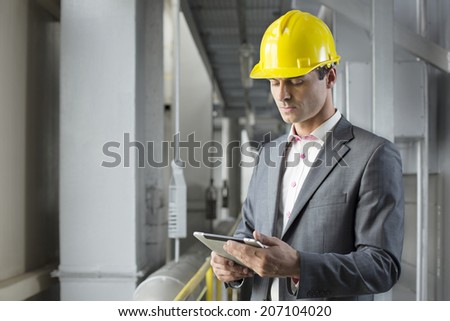 Young male architect using tablet computer in industry