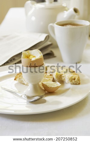 Closeup of half eaten hard boiled egg on dining room table with tea