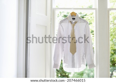 Dress shirt and tie on hanger at domestic window