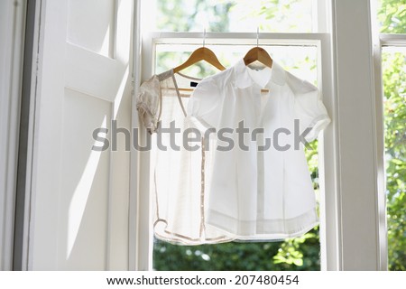 Blouses on hangers at domestic window