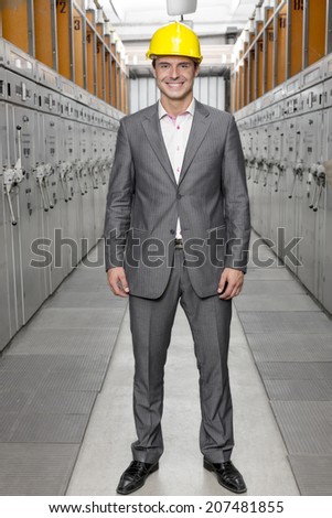 Full length portrait of smiling young male supervisor standing in control room