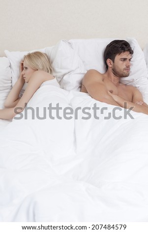 Angry young couple avoiding each other in bed