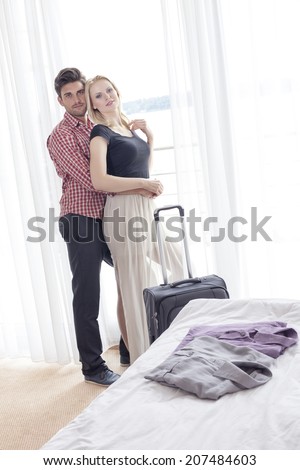 Portrait of young man embracing woman from behind in hotel room