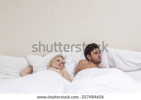 Angry young man ignoring woman in bed