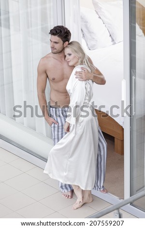Full length of loving young couple spending quality time at balcony doorway