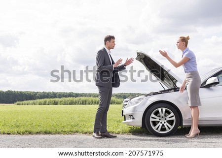 Full length side view of business couple arguing over broken car at countryside