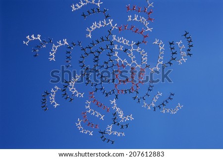 Large group of skydivers flying in formation of flower against blue sky