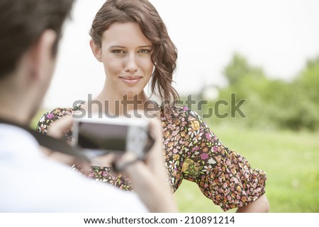 Portrait of confident woman being photographed by man in park