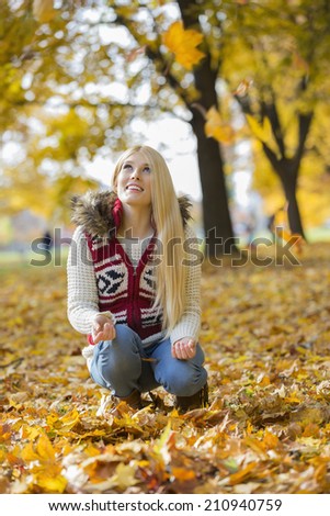 Young woman crouching while looking up in park during autumn