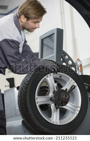 Cropped image of automobile mechanic repairing car\'s wheel in workshop