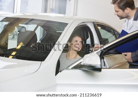 Female customer receiving car key from mechanic in automobile repair shop
