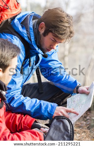 Male backpackers reading map in forest