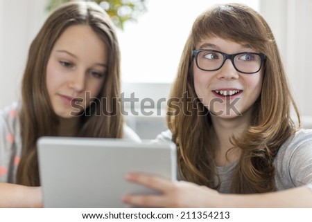 Happy girl with sister using digital tablet at home