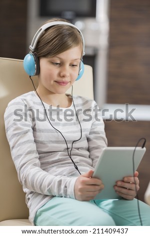 Cute girl listening music while using digital tablet at home