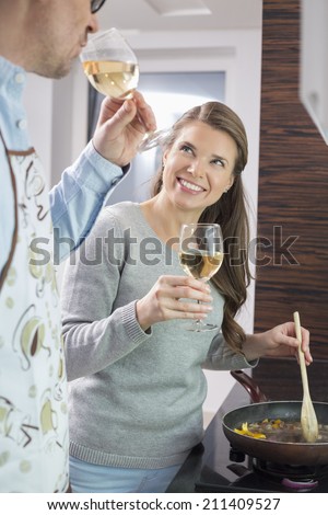 Happy woman having wine with man while cooking in kitchen