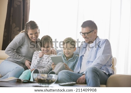 Cheerful family using tablet PC together in living room