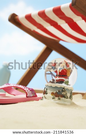 Souvenir santa snow globe under deckchair on beach close up