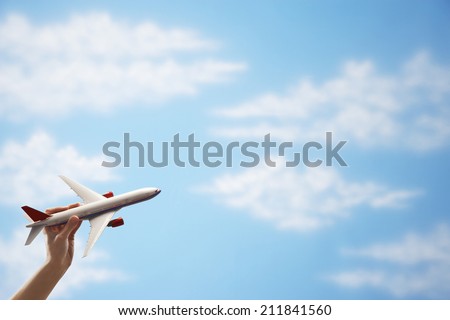 Closeup of woman\'s hand flying toy plane against cloudy sky