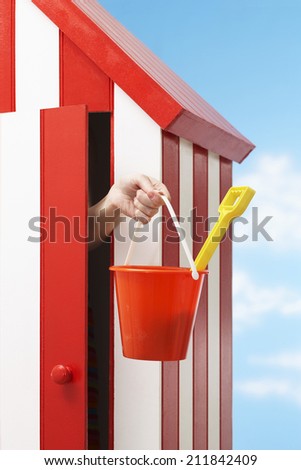 Woman\'s hand holding bucket and spade in beach cabin