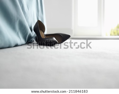Closeup surface view of high heeled shoes by bed