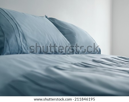 Closeup of a bed with blue linen in the bedroom
