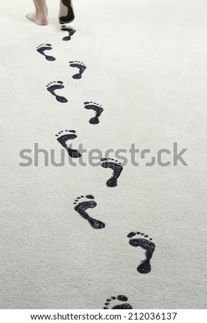 Young woman leaving black footprints on carpet