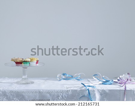 Streamers and cup cakes on platter on table