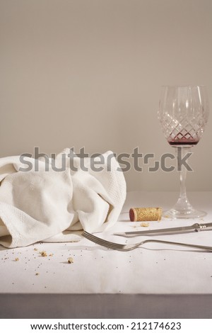 Wine glass, cutlery, dish cloth on messy table